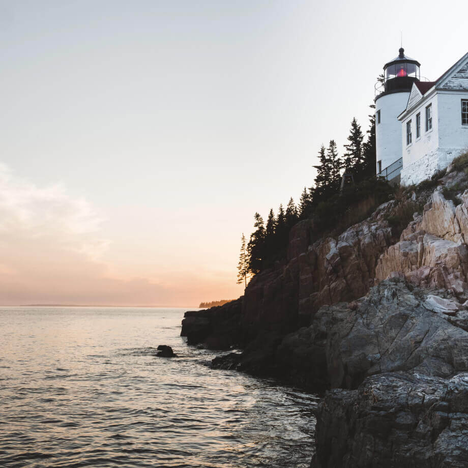 A lighthouse on a rocky hill beside the sea in Maine, USA